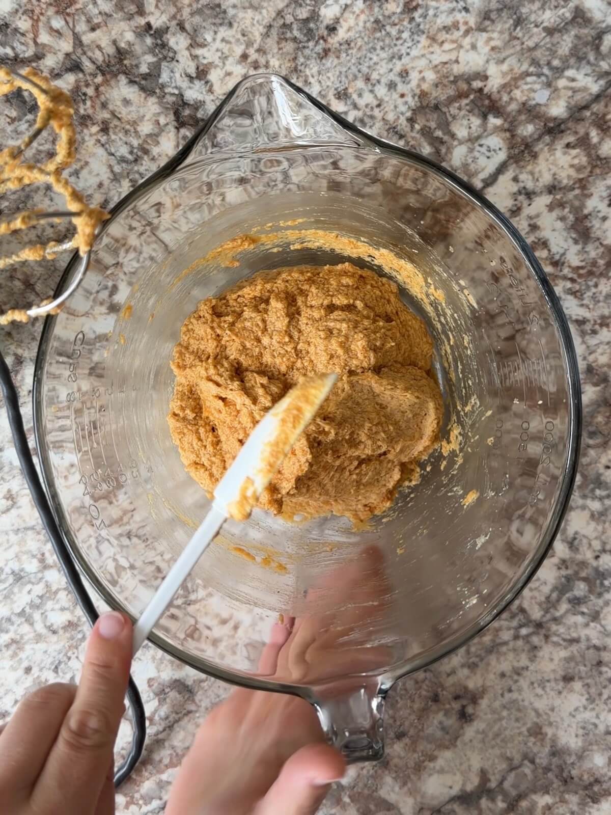 Sourdough discard, pumpkin puree, and other wet ingredients being mixed together in a glass bowl.