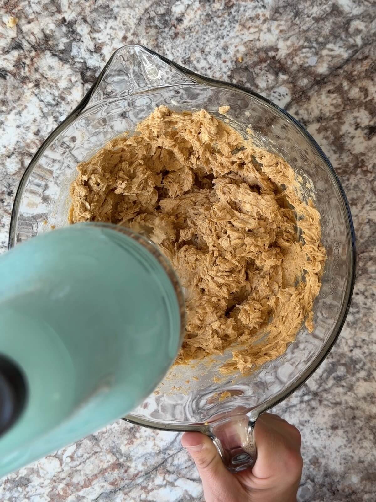 Sourdough pumpkin oatmeal cookie batter being mixed together with a hand mixer.