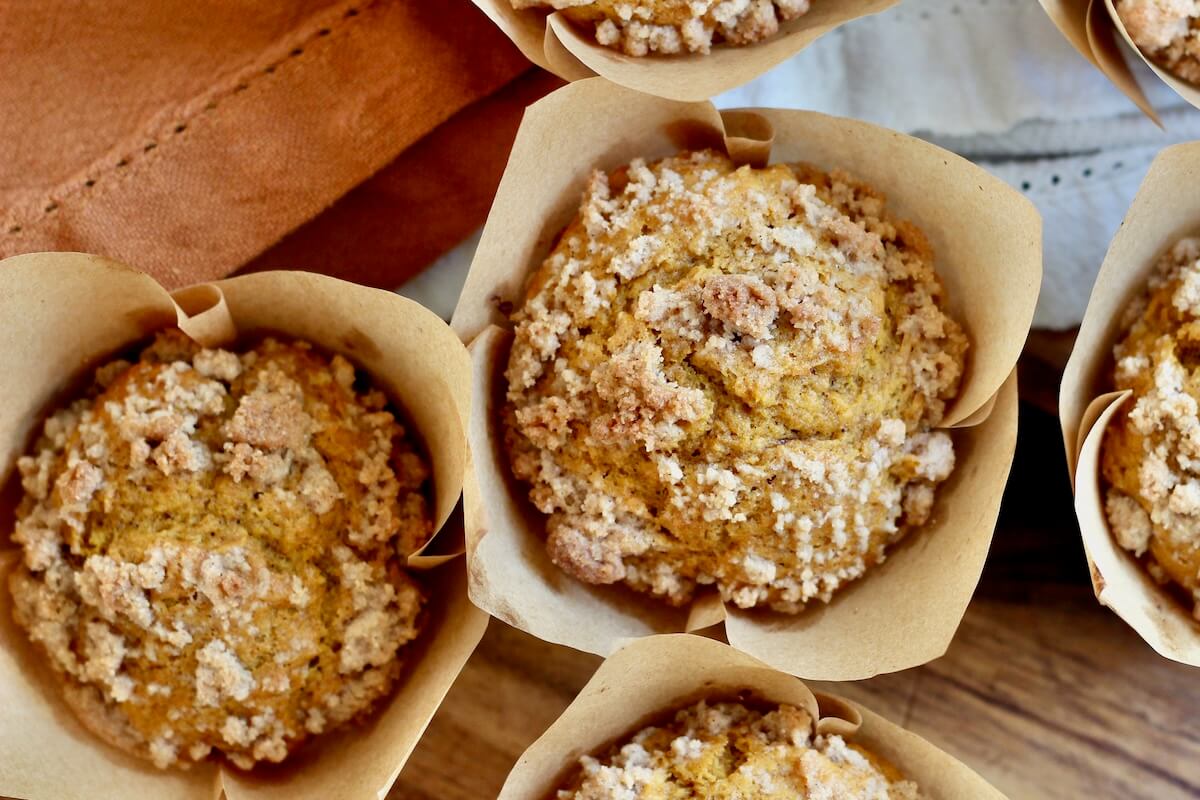 Sourdough pumpkin streusel muffins in parchment wrappers on a table.