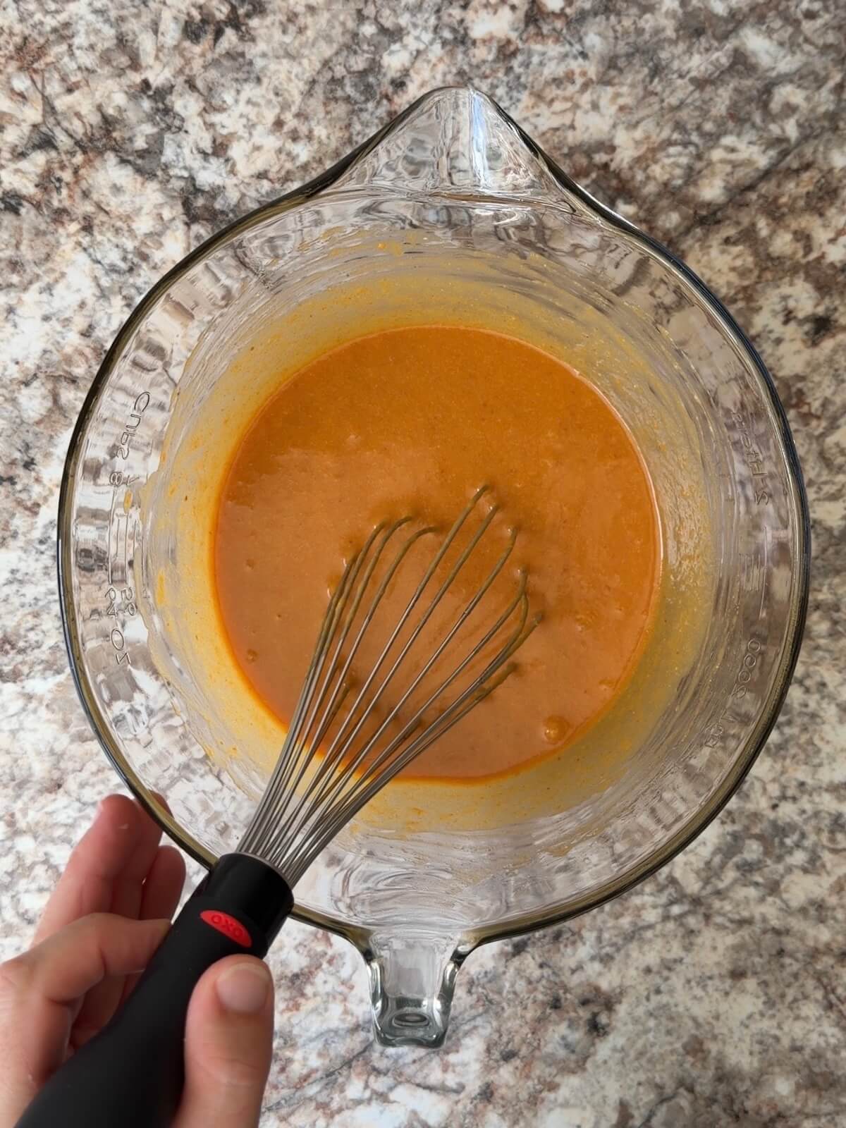 The wet ingredients, including sourdough discard and pumpkin puree, whisked together in a large mixing bowl.