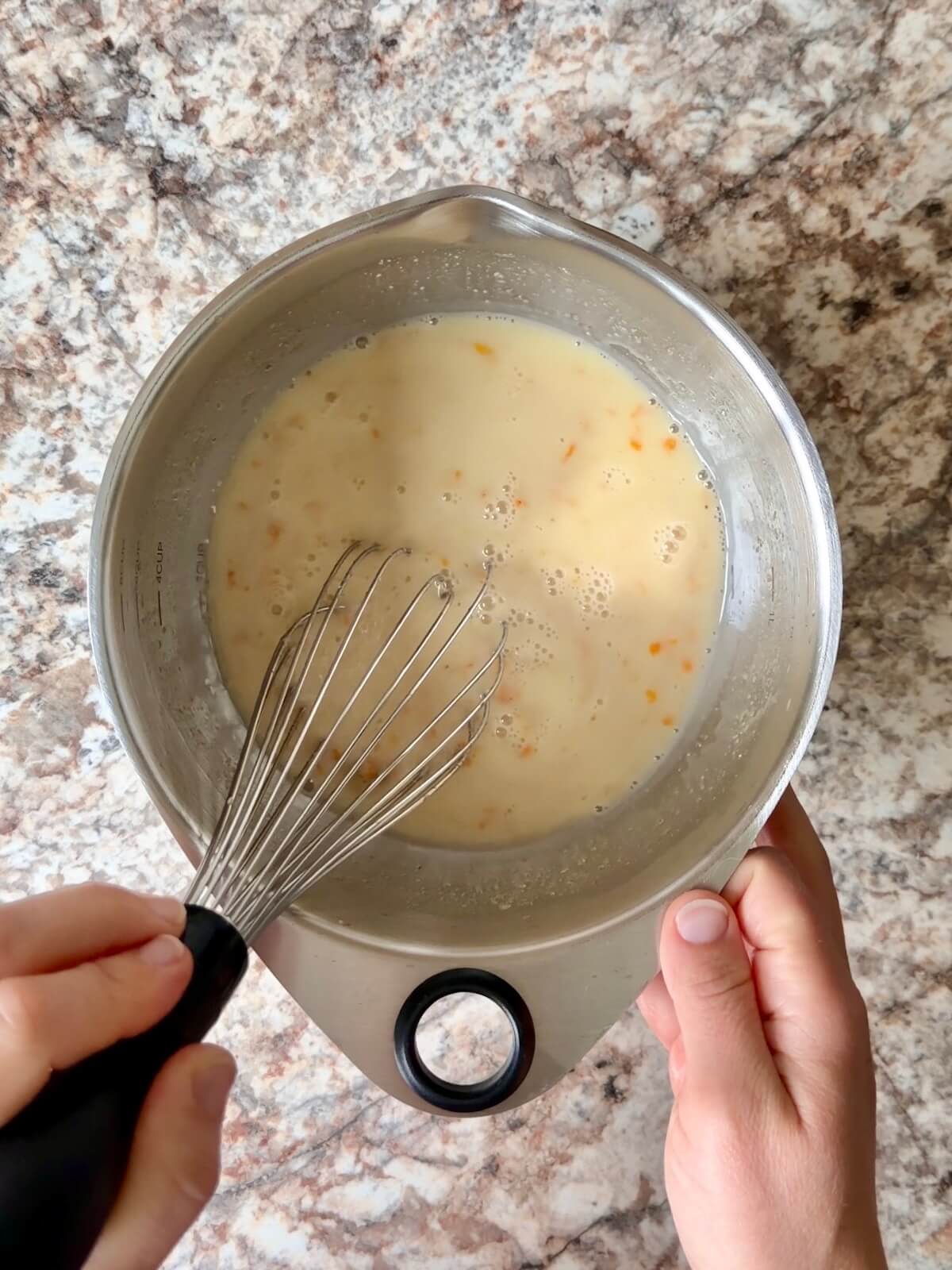 Orange juice, zest, water, and active sourdough starter whisked together in a bowl.