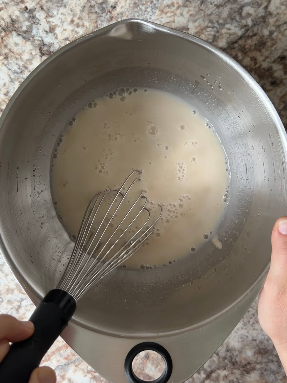 Water and sourdough starter whisked together in a bowl.