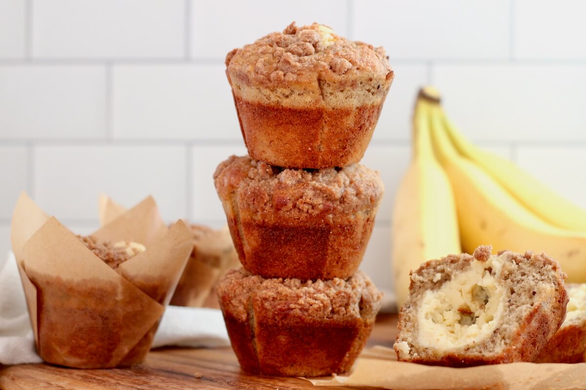 A stack of three sourdough banana muffins with cinnamon streusel and cream cheese filling.