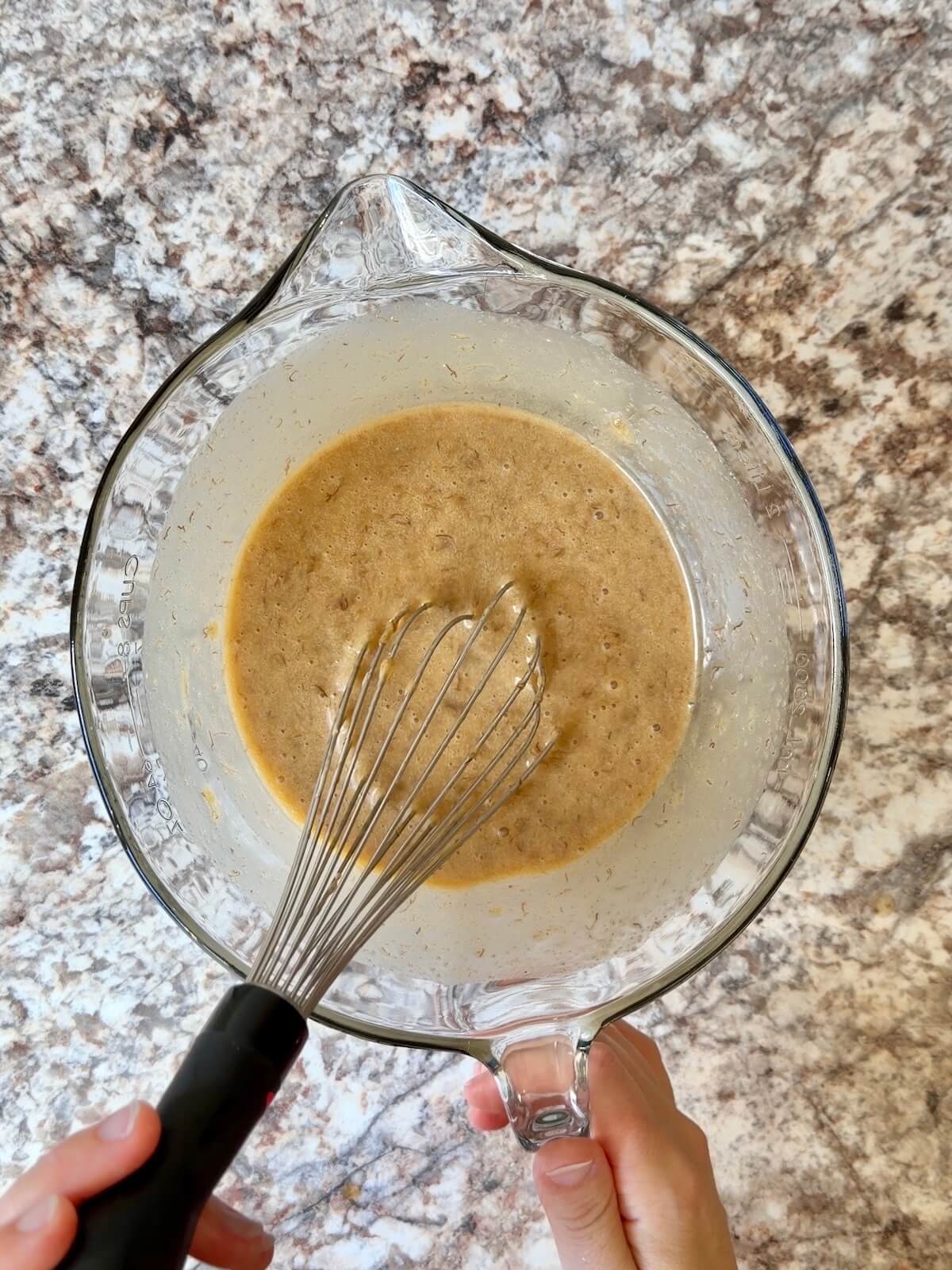 Sourdough discard, mashed banana, and other wet ingredients whisked together in a bowl.