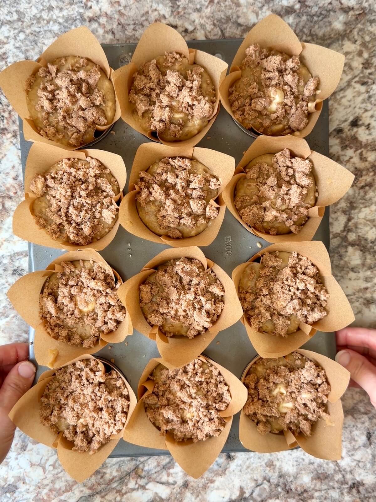 Sourdough banana cream cheese muffins with cinnamon streusel topping in a paper lined muffin pan before baking.
