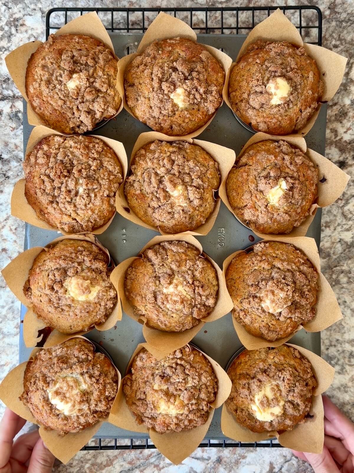 Baked sourdough banana muffins with cinnamon streusel and cream cheese filling in a muffin pan.