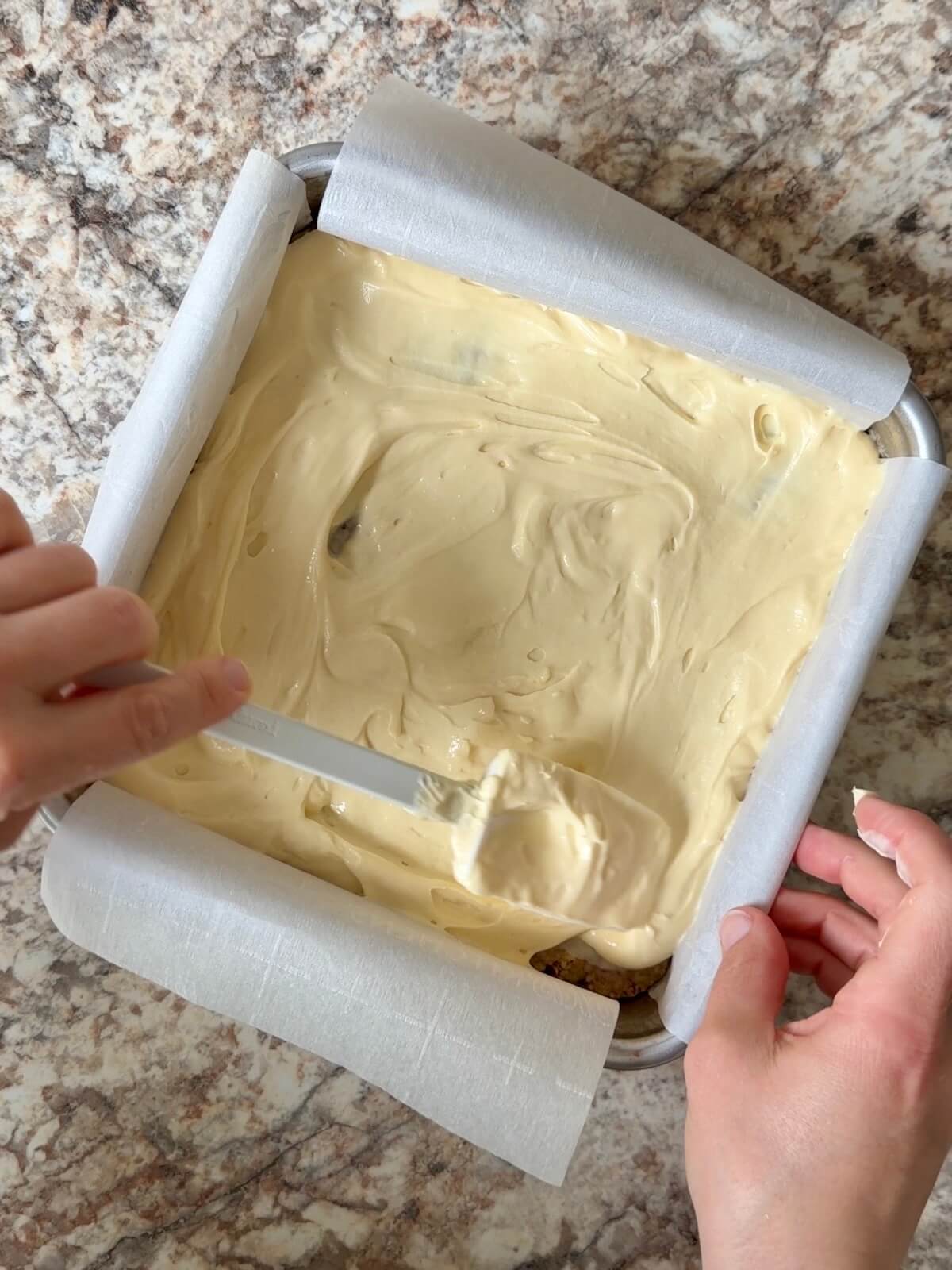Cheesecake mixture being spread on top of the par-baked pecan cookie crust.