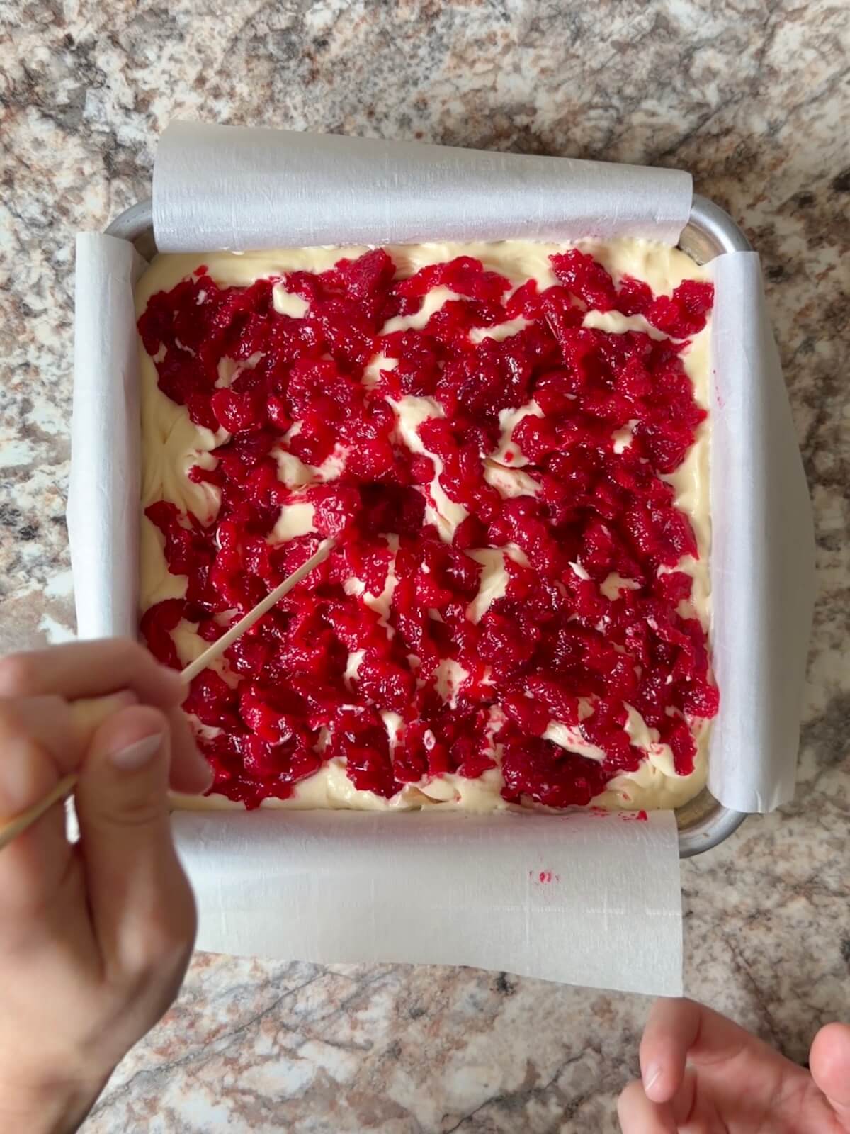 Cranberry jam being swirled into the cheesecake layer.