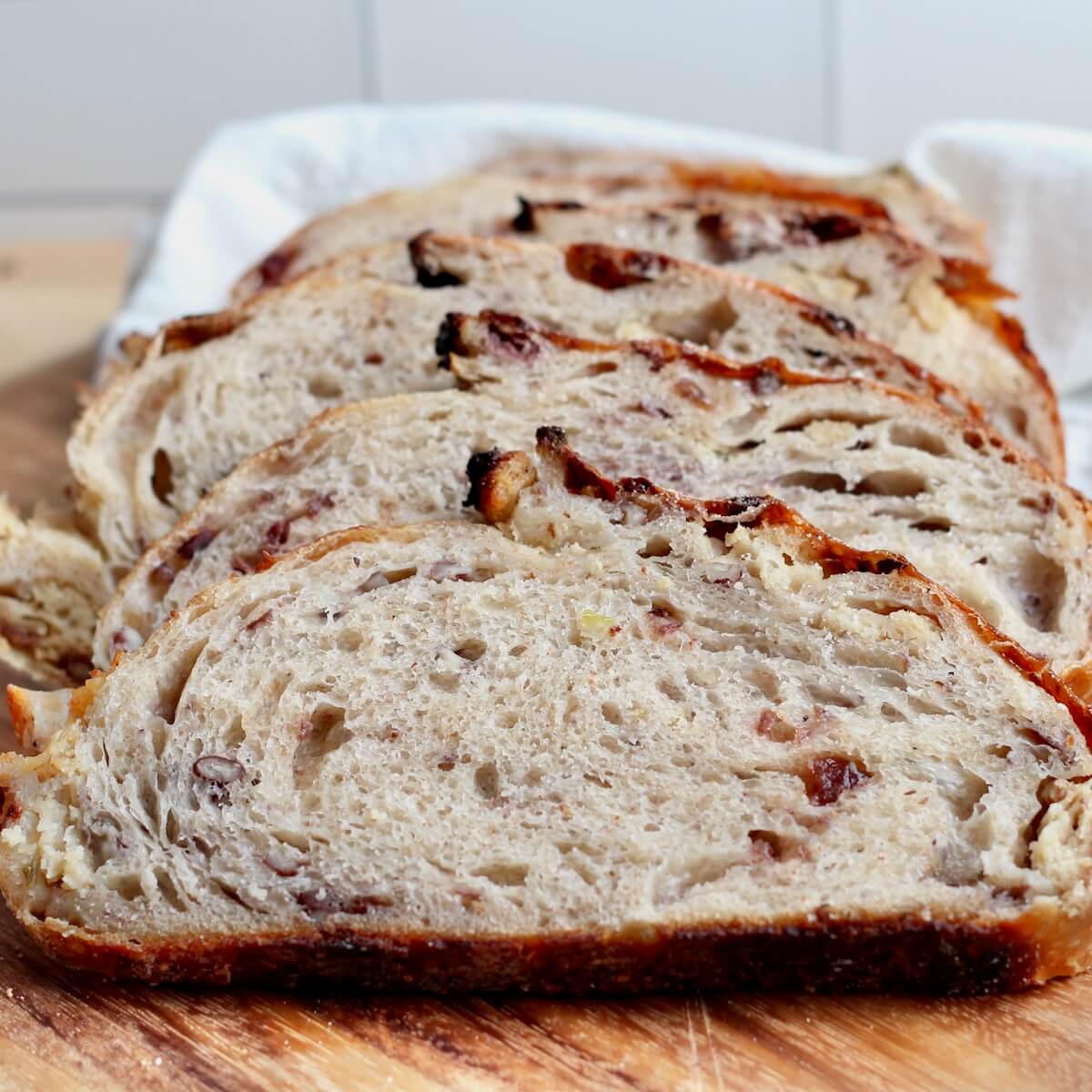 A sliced loaf of Thanksgiving stuffing sourdough bread on a wooden cutting board.