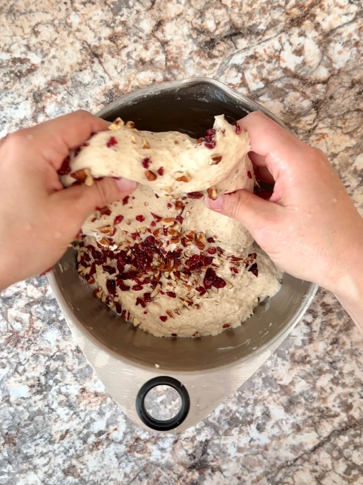 Chopped pecans and dried cranberries being stretched and folded into the dough.